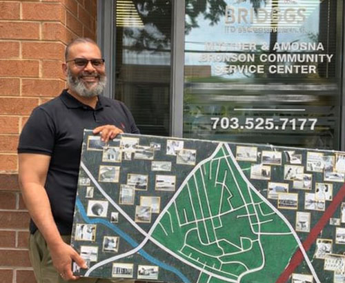 Man holding a large map with photos in front of the Bridges to Independence door